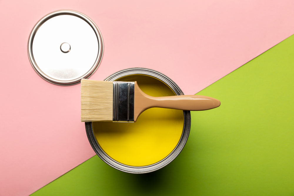 Open yellow paint can with brush