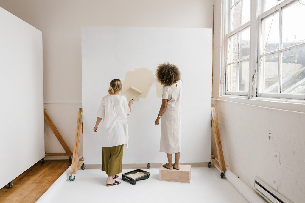 Two women painting on a large canvas